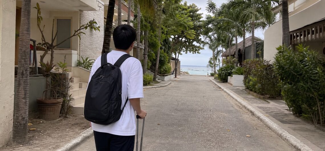 セブ島のホテルが並ぶ海辺の道を歩く旅行者