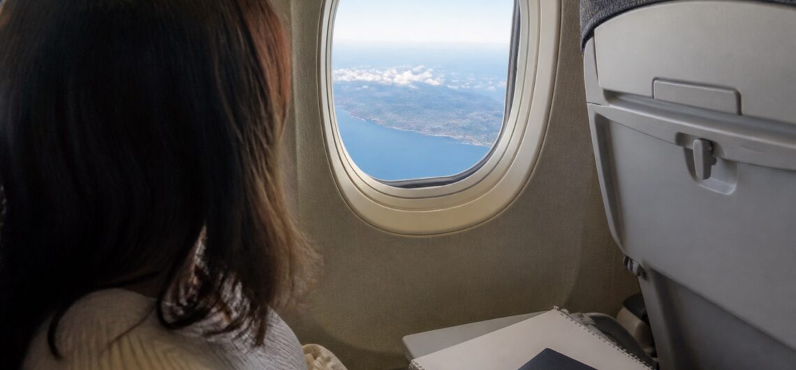 成田からセブ島へのフライトで窓の外を眺める旅行者