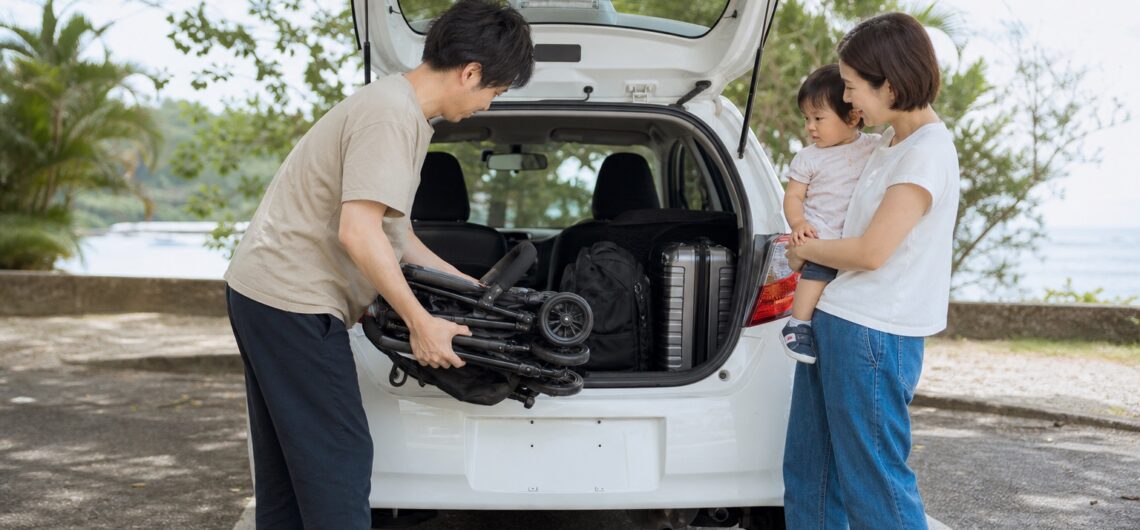 レンタカーの荷室へ折りたたんだベビーカーを積む家族